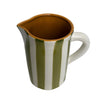 Ceramic pitcher with brown interior, green and white exterior on a light gray background