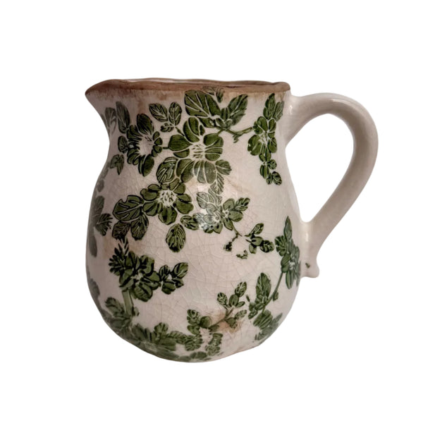 Ceramic pitcher with green floral patterns on a white background