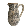 Ceramic pitcher with floral patterns on a plain background