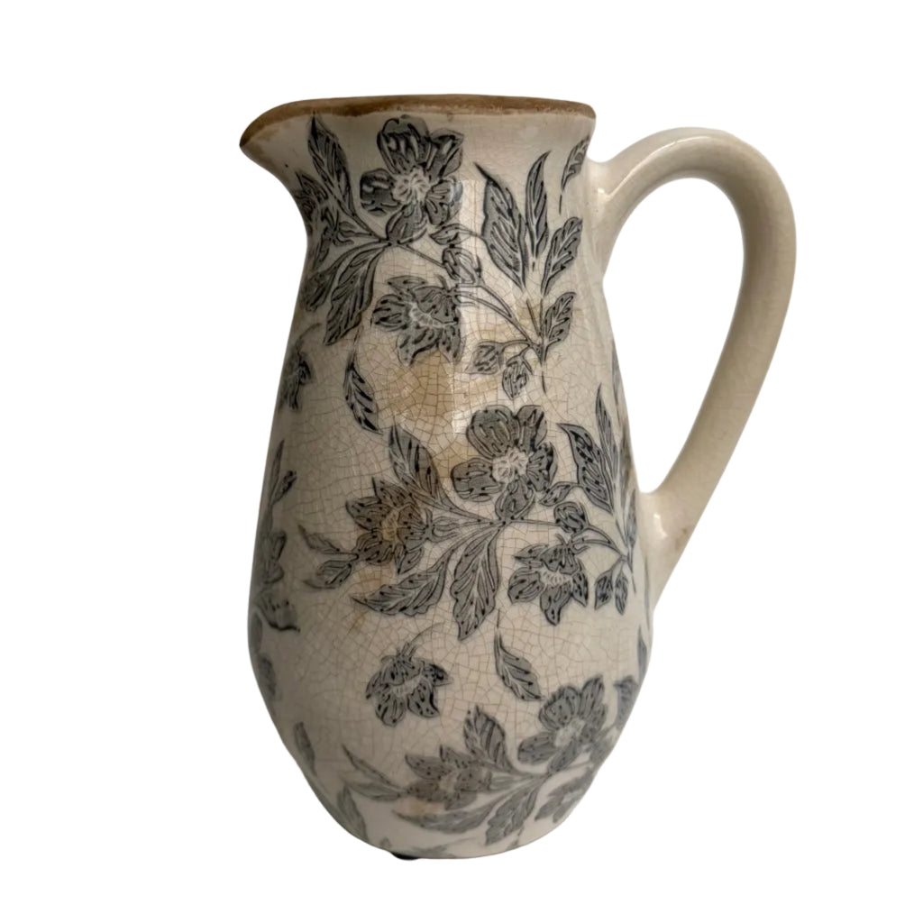 Ceramic pitcher with floral patterns on a plain background